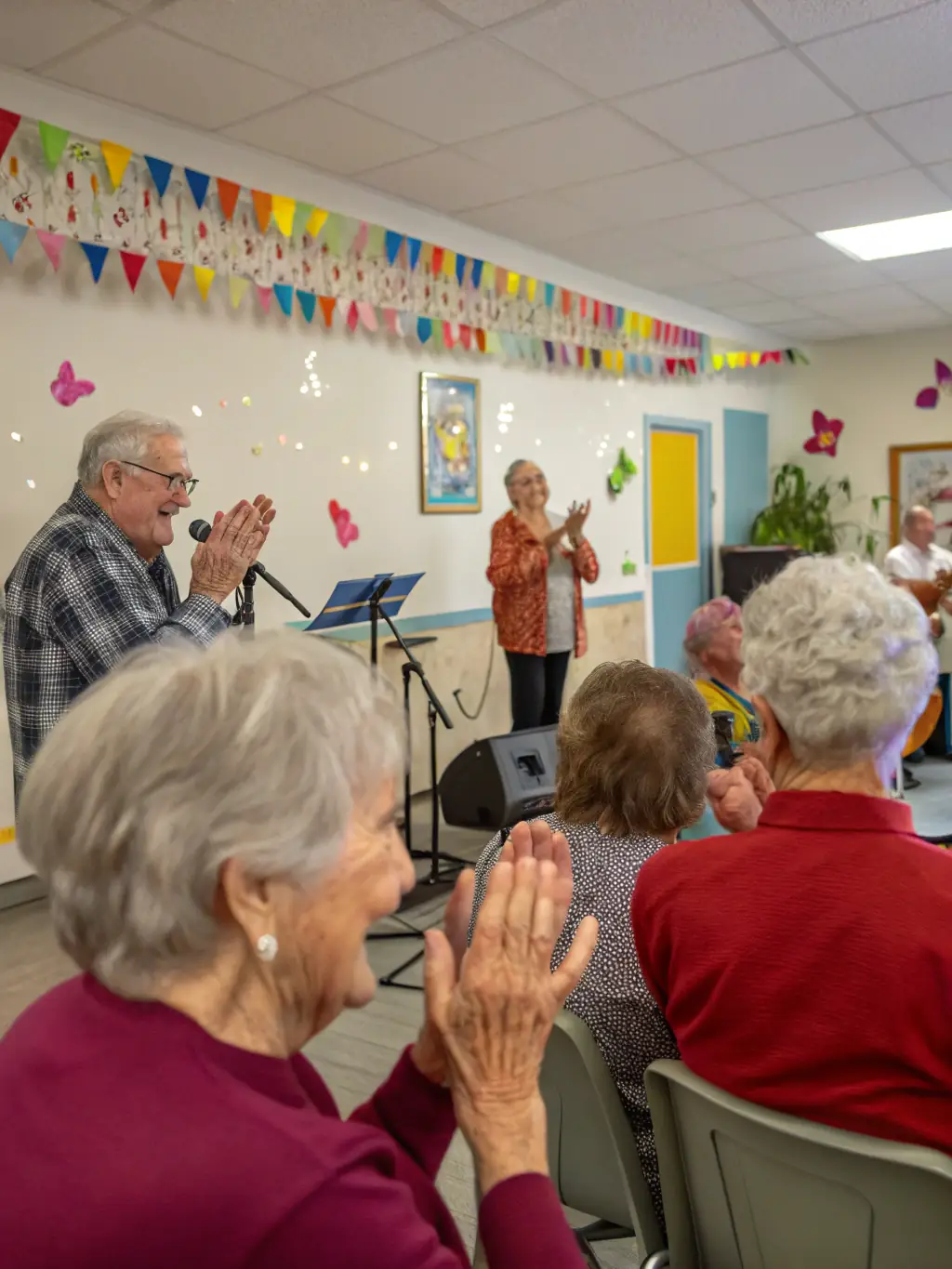 A heartwarming photo of elderly residents enjoying a musical performance in a care home, with musicians engaging with them.